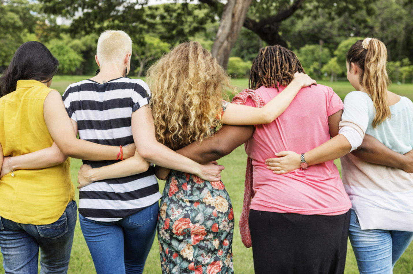 Five women facing away from camera, with arms around each other