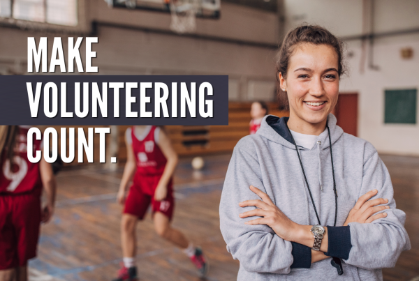 A volunteer basketball coach, standing in a gym with her arms crossed and smiling. Text reads "Make volunteering count"